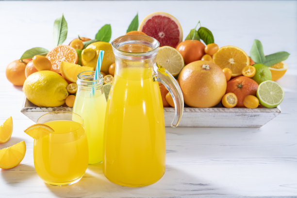 在白色的木桌上摆放着各式各样的柑橘类果汁，如橙汁和柠檬汁图片下载