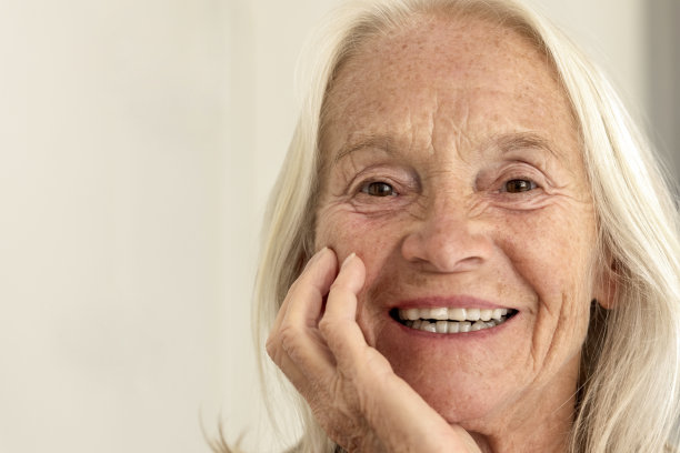 微笑的老年妇女与手下巴的特写肖像，前面的观点，背景与复制空间图片下载
