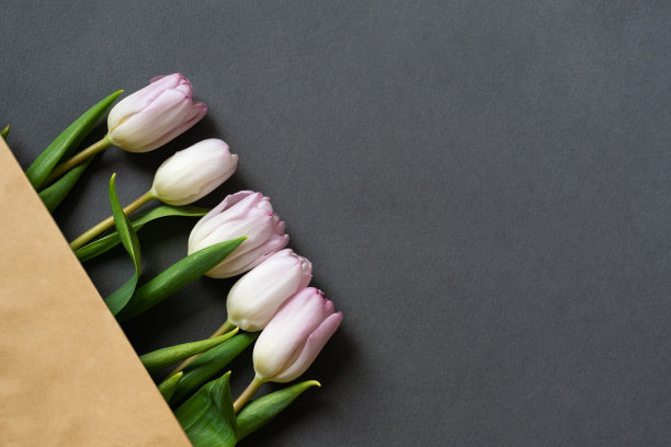 春天的花束粉红色郁金香在米色纸袋上灰色的纸背景图片下载