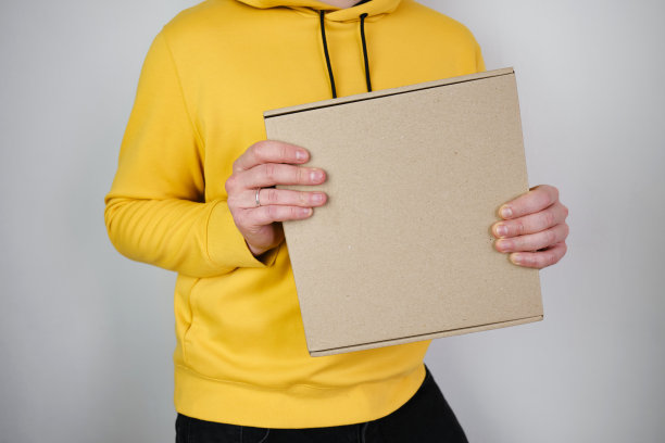 一个男人手里拿着一个纸盒。有新包裹的人。邮政服务,交货。牛皮纸。礼物盒,礼物。盒子特写。空包装，空空间。沟通的人。纸箱图片下载