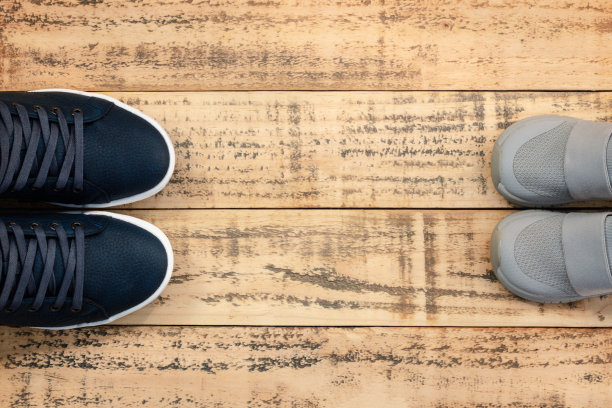 大的和小的运动鞋鞋在木制背景。父亲节的庆祝活动。图片下载