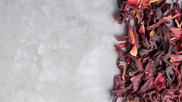 干燥的木槿花瓣在灰色的背景上。花红色的木槿茶在水泥表面。Karkade，红茶，芳香木槿茶。前视图。本空间图片下载