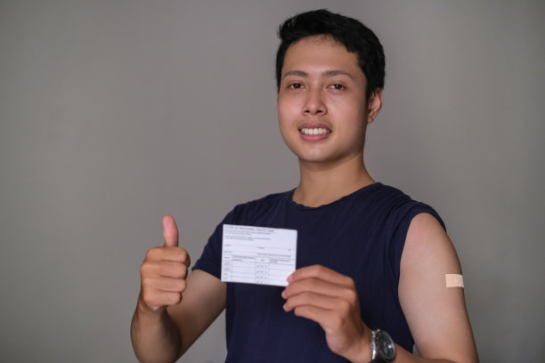 年轻的印尼男子竖起大拇指，展示他的疫苗接种卡图片下载