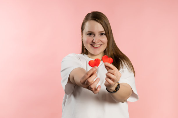 微笑的女孩，棕色头发，白色t恤，粉色背景，红心图片下载