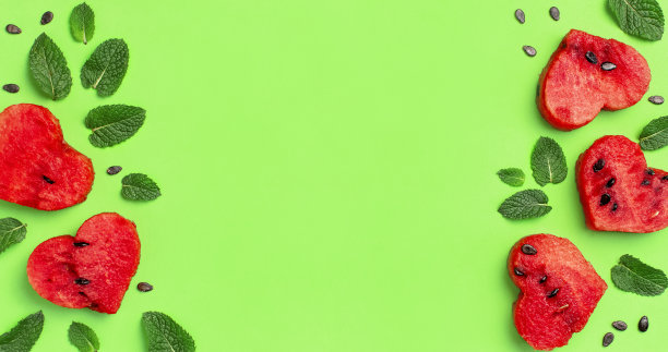 创意夏日美食概念。在绿色的背景上一个心形和薄荷叶形状的成熟红色西瓜多汁的切片框架。平躺，顶视图，复制空间。西瓜模式图片下载