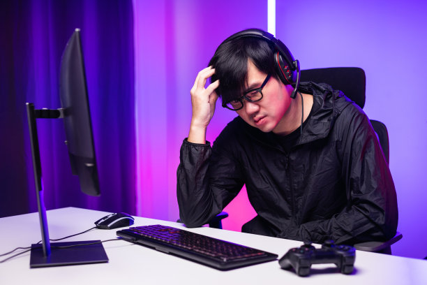 愤怒的亚洲玩家玩电脑。他在比赛中输了。错过了成为锦标赛冠军的机会。不高兴心烦的人流视频游戏在线和输了。图片下载