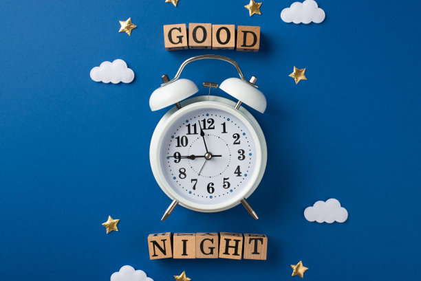 俯视图照片，一个大警报与散落的五彩纸屑形状的星星和云，和木制立方体的文字在深蓝色的背景图片下载