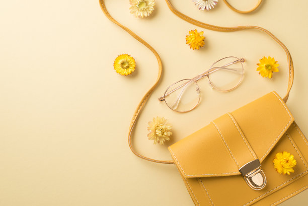 俯视图照片的女人的一天组成黄色皮革手袋时尚的眼镜和田野花在孤立的米色背景与空白的空间图片下载