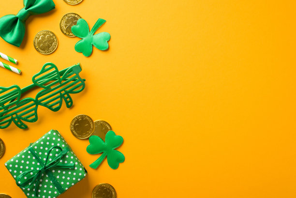 圣帕特里克节装饰的俯视图照片三叶草形状的派对眼镜稻草绿色蝴蝶扣礼盒与圆点图案三叶草和金币在孤立的黄色背景与空白空间图片下载