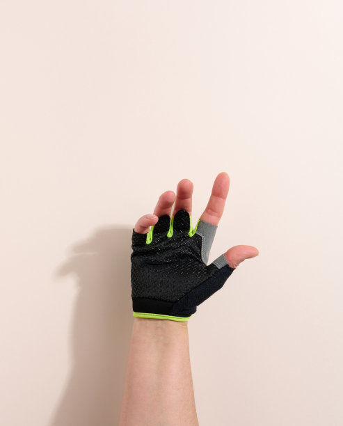 黑色运动手套在一个女性的手，米色背景。身体的一部分被抬起来了图片下载