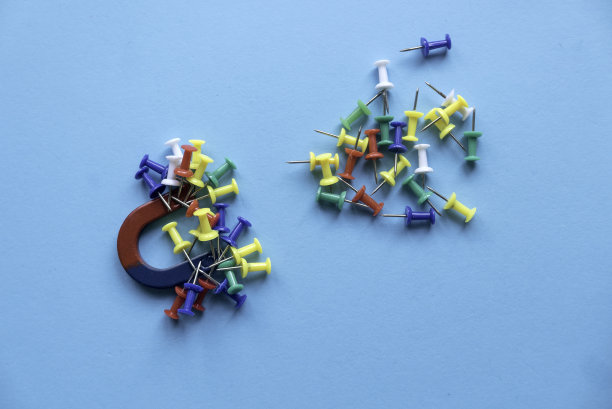 马蹄形磁铁，在蓝色背景上挂着一串彩色的大头针。图片下载