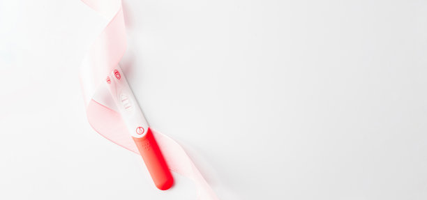 怀孕测试孤立。孕妇试验阳性，白色背景上有粉色丝带。医疗保健妇科，孕产期产妇的观念。图片下载