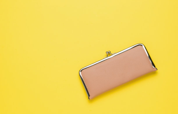 一个色彩柔和的女人的钱包，亮黄色的背景。平的。图片下载