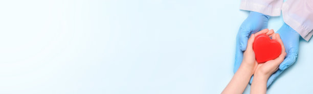 一个医生和一个孩子的手握着一颗红心。健康理念、慈善理念、器官捐赠理念。世界心脏和卫生日。space.Banner基金等。图片下载