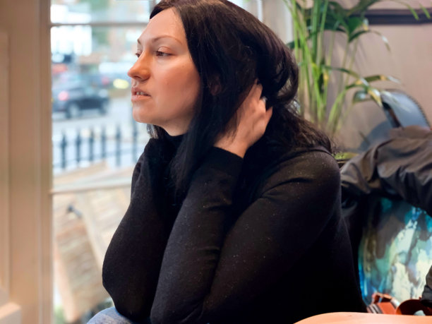 年轻的成年女子坐在窗边图片下载