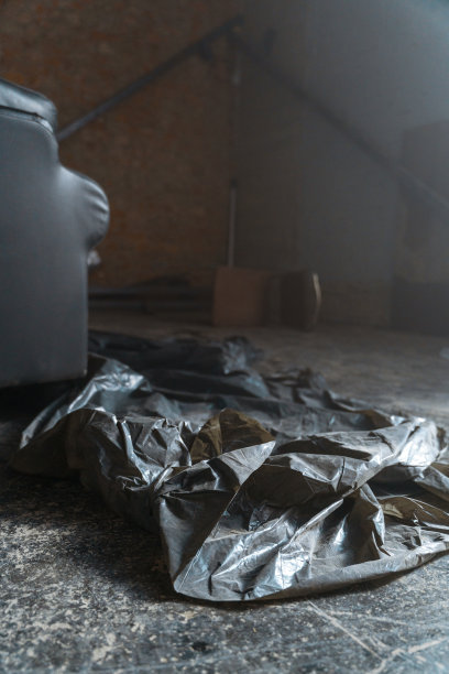 光天化日之下，废弃仓库肮脏的地板上放着一个黑色的垃圾塑料袋图片下载