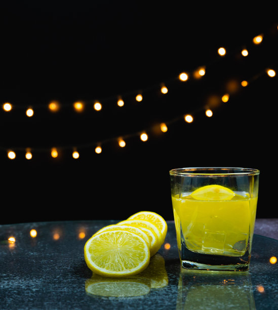 将新鲜柠檬切片放在桌上的柠檬汁杯旁边图片下载