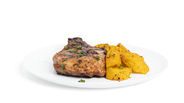 酱汁猪肉排和烤土豆放在盘子里，孤立在白色的背景上图片下载