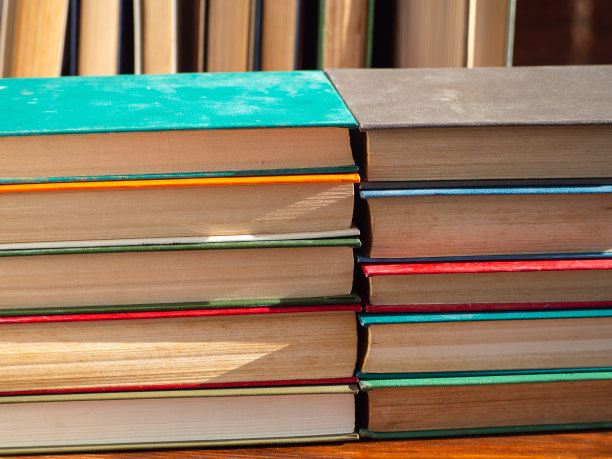 一堆堆精装本发黄的旧书，被阳光照亮。知识，科学，求知欲，回到学校。木桌上五颜六色的书。自我教育图片下载