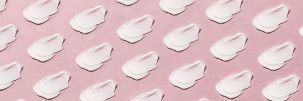在粉红色的背景上涂抹奶油。图片下载