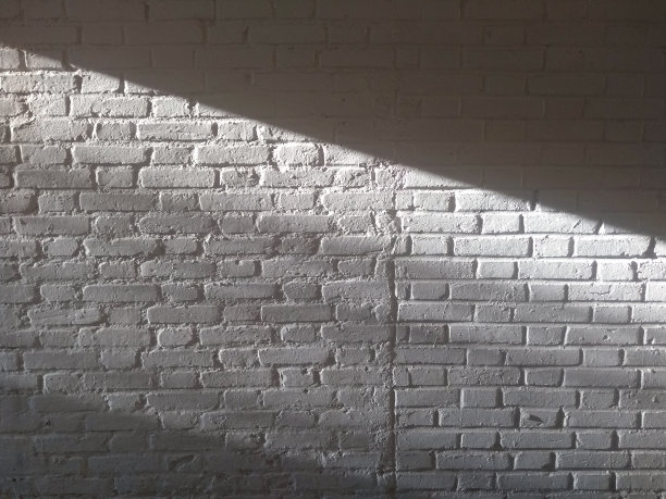 白色砖墙，阳光斜射入墙内，形成光影对比。图片下载