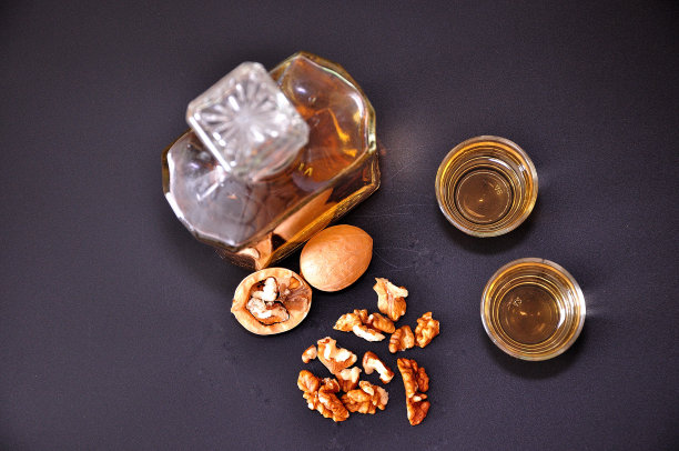 自制核桃利口酒，一瓶烈酒和两个玻璃杯，白色背景。图片下载