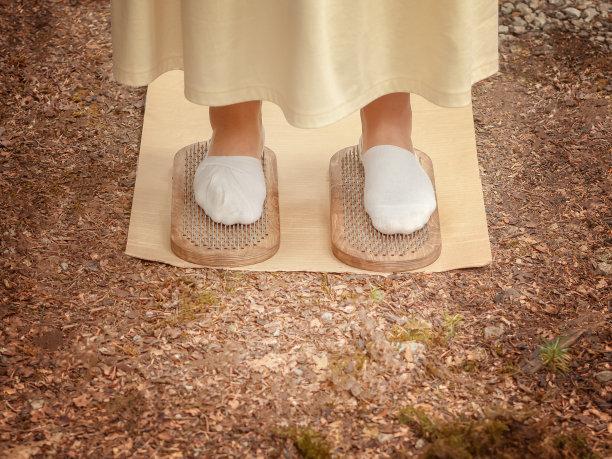 穿着长裙子和白袜子的女人的腿站在两块有尖钉的木板上。苦行僧董事会图片下载