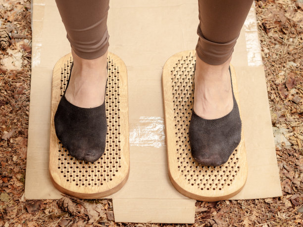 穿着打底裤和黑袜子的腿站在两块有尖钉的木板上。苦行僧董事会图片下载