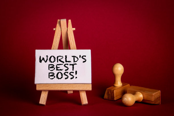 世界上最好的老板。在红色背景上的文本和木制邮票的微型画架图片下载
