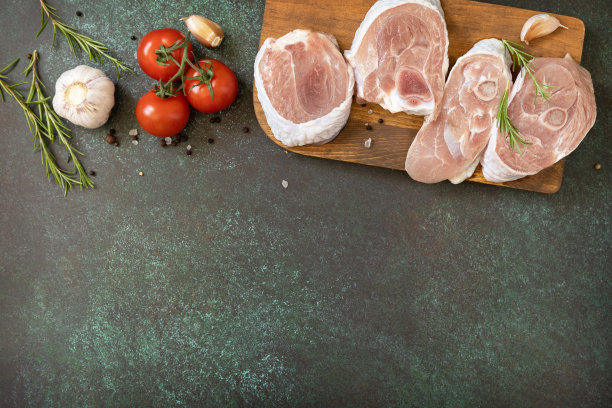 在深色的石头桌面上放上新鲜的牛排、生火鸡、迷迭香和香料。用于烧烤的生牛肉排。俯视图平坦的背景。副本的空间。图片下载