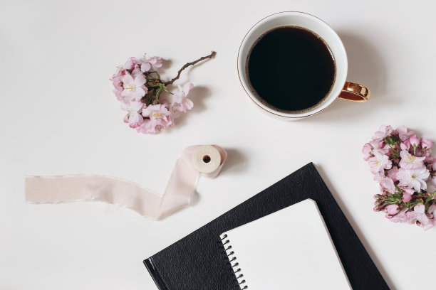 复活节，春天静物。空白的日记模型。一杯咖啡，盛开的粉红色日本樱桃树枝孤立在白色的桌子背景上。家庭办公室。早餐,休息的概念。平躺，俯视图。图片下载