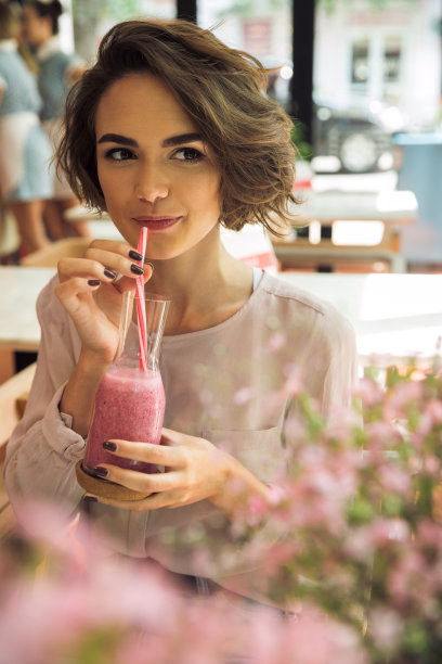 漂亮的年轻女人用吸管喝冰沙图片下载