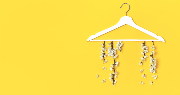 春天的花枝挂在黄色背景的白色木制衣架上。春销概念折扣店购物空衣架促销设计。创意时尚旗帜。平躺顶视图复制空间。图片下载