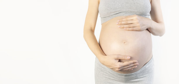 美丽的年轻孕妇手放在她的腹部白色背景。对孩子，怀孕和母亲的期望的概念。孕妇的温柔照片。特写，文字的位置图片下载