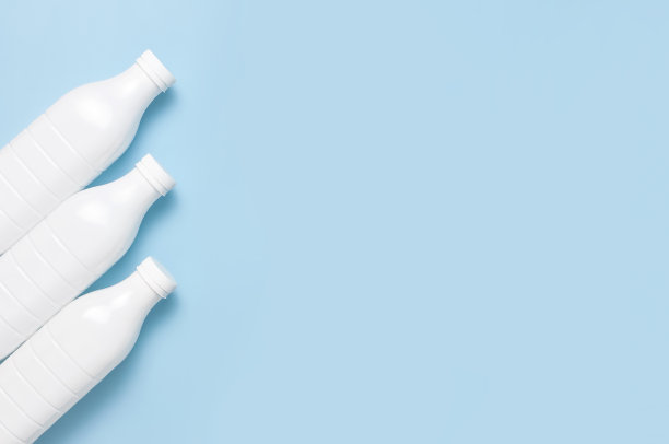 白色塑料瓶容器的奶制品在蓝色背景顶视图平躺。塑料开菲尔酸奶奶瓶。包装模板模型。设计的布局图片下载