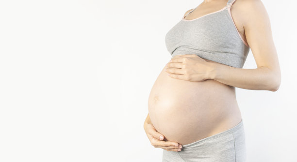 美丽的年轻孕妇手放在她的腹部白色背景。对孩子，怀孕和母亲的期望的概念。孕妇的温柔照片。特写，文字的位置图片下载