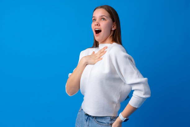 震惊和惊讶的年轻少女在蓝色的背景下图片下载
