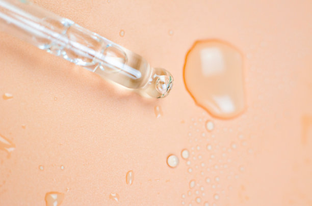 移液器和液体在桃色背景上的特写，选择性聚焦。胶原蛋白，透明质酸，皮肤护理。人体护理化妆品实验室研发图片下载