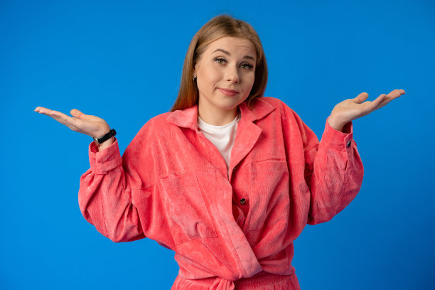 一个美丽的困惑的年轻女孩的肖像在蓝色的背景图片下载