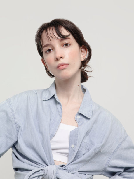 美丽的年轻黑发女人的肖像穿着白色露背上衣和蓝色牛仔布衬衫专业的自然化妆白色背景图片下载