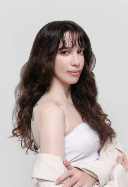 美丽的年轻黑发女人的肖像穿着白色露背上衣和米色夹克专业的自然化妆白色背景图片下载