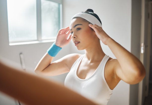 这张照片拍摄的是一个漂亮的年轻女子在网球赛场的更衣室里对着镜子检查自己图片下载