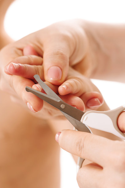 妈妈牵着孩子的手剪指甲。图片下载