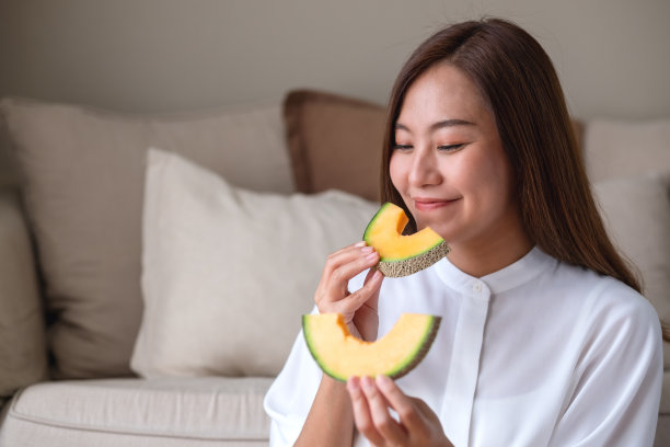 一个年轻女子拿着两片哈密瓜吃图片下载