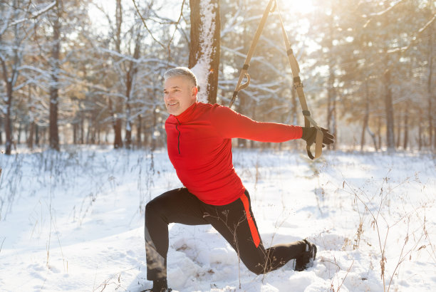活跃的成熟运动员在户外与吊带教练一起锻炼，在冬季公园使用吊带进行训练图片下载