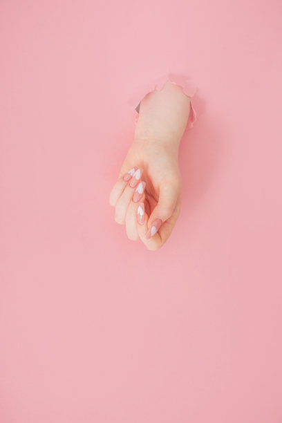 女性的手与美丽的长指甲与指甲在粉红色的纸背景图片下载