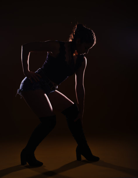 一个性感的女模特在黑暗的背景上摆姿势的高对比度剪影照片图片下载