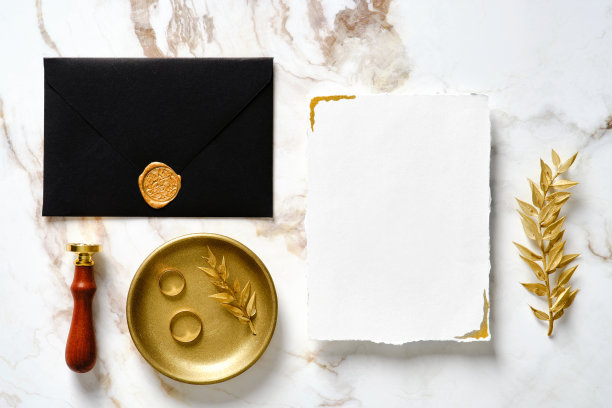 优雅的婚礼文具套装。婚礼请柬模板，黑色信封，金戒指，蜡印章印章，大理石桌子上的金色树枝。图片下载