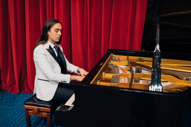 侧视图一个年轻的，有才华的艺术家坐在钢琴前，为他的下一次演出演奏和排练。图片下载