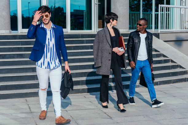 身着正装的现代多民族青年在办公大楼外谈生意图片下载